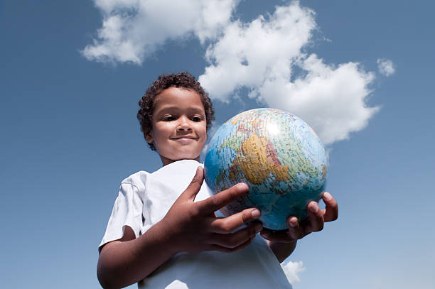An image picturing a young boy holding the Earth in his hands